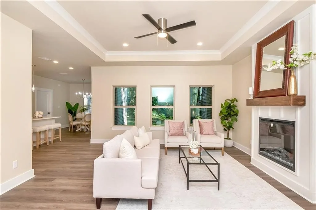Living room with a fireplace, tall windows and a ceiling fan