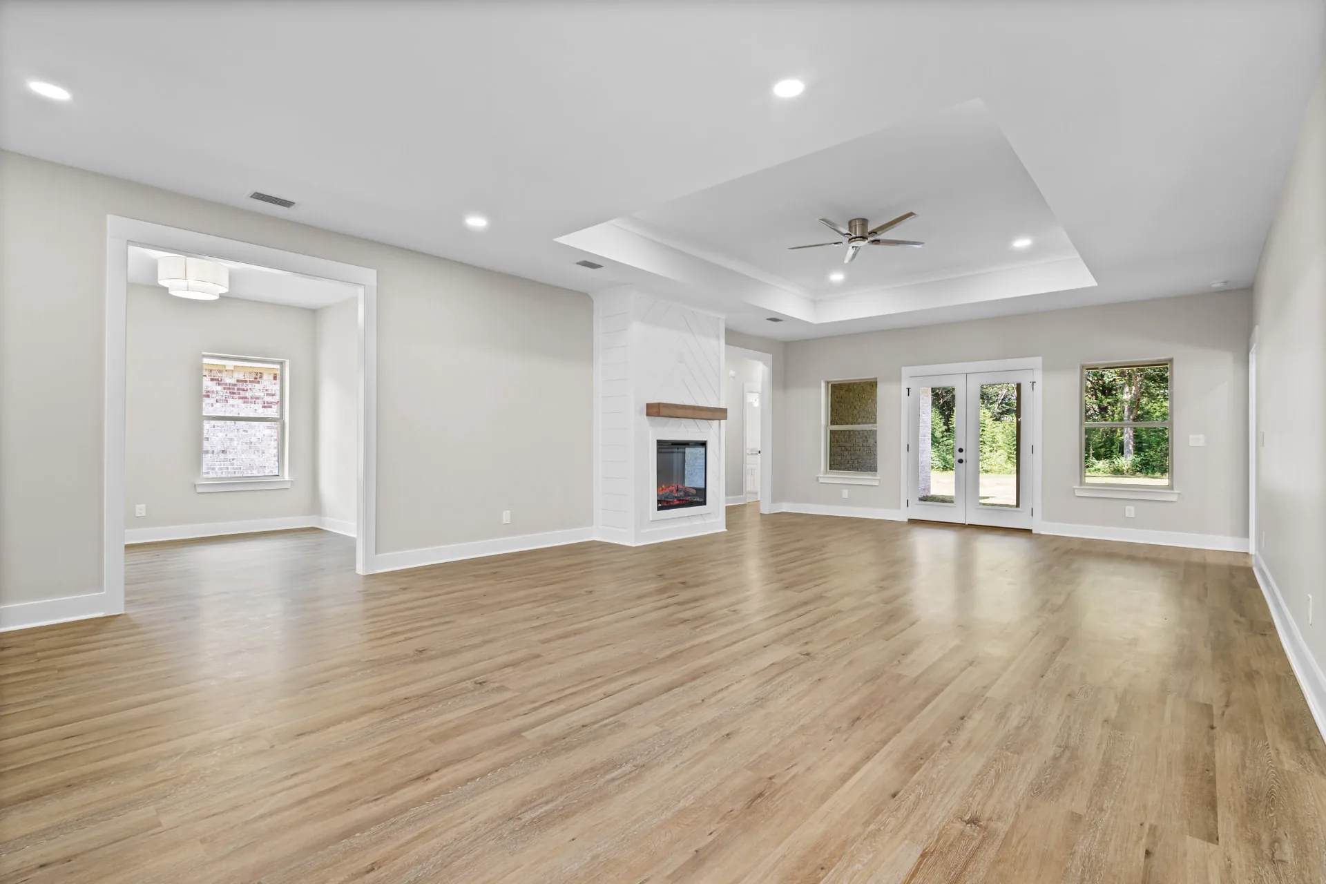 New construction great room with tray ceiling and shiplap fireplace