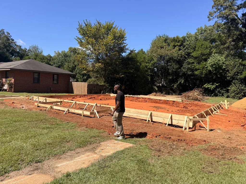 Joe Slone walking beside the foundation formwork at the Dalraida build in Montgomery, Alabama