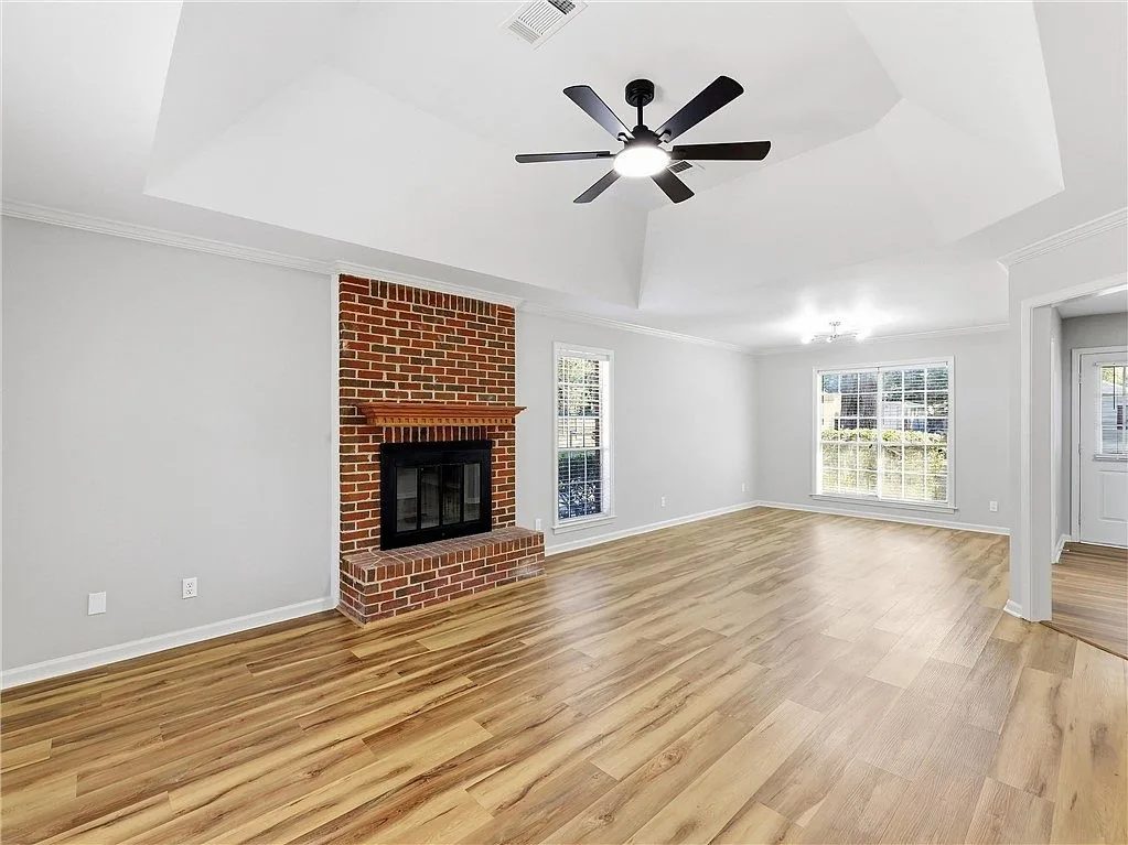 Living room with a brick fireplace and ceiling fan