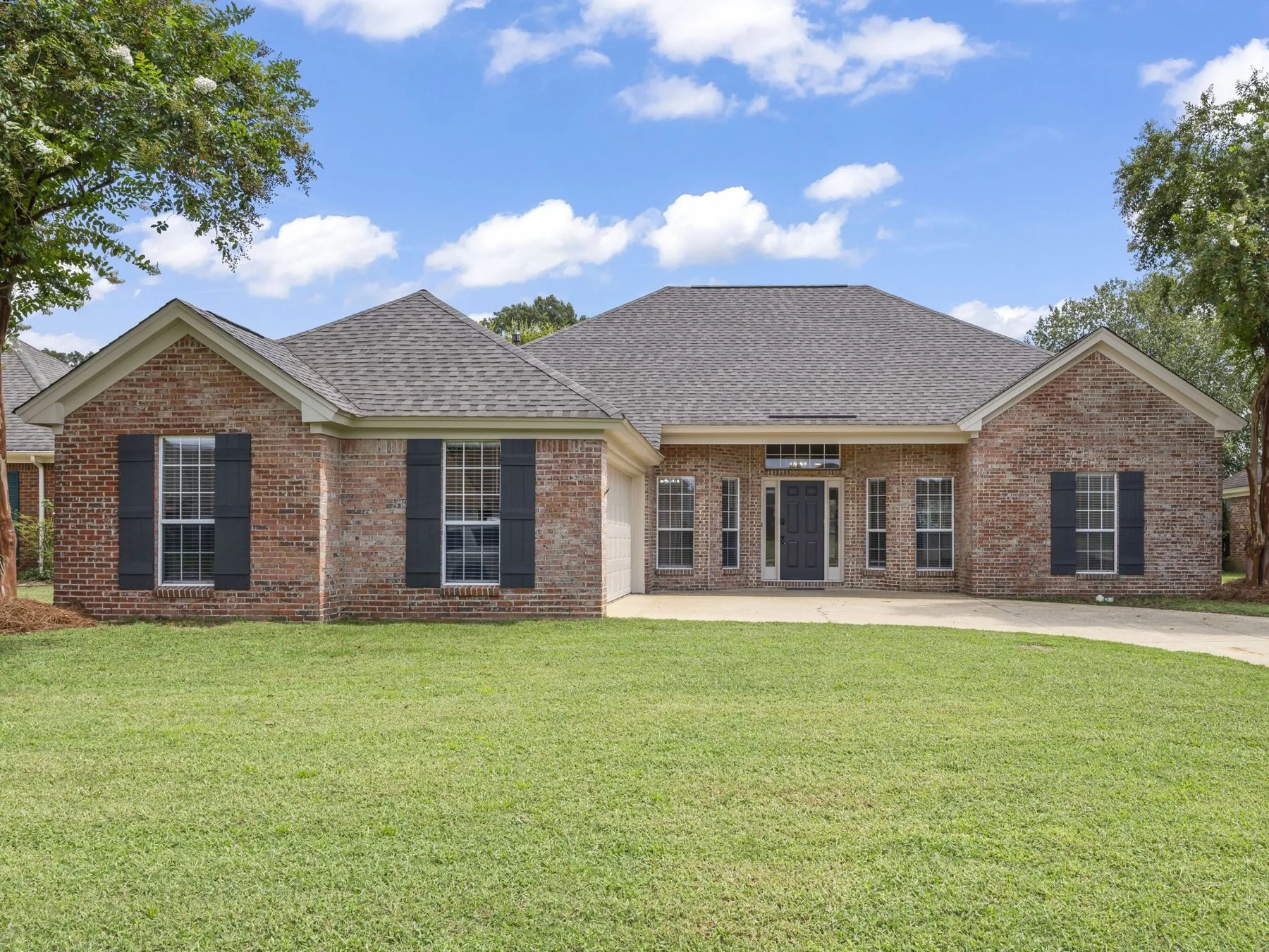 Brick ranch home with dark shutters and a covered front entry