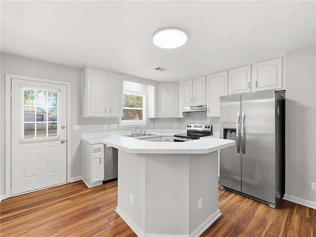 Kitchen with a white island and stainless refrigerator