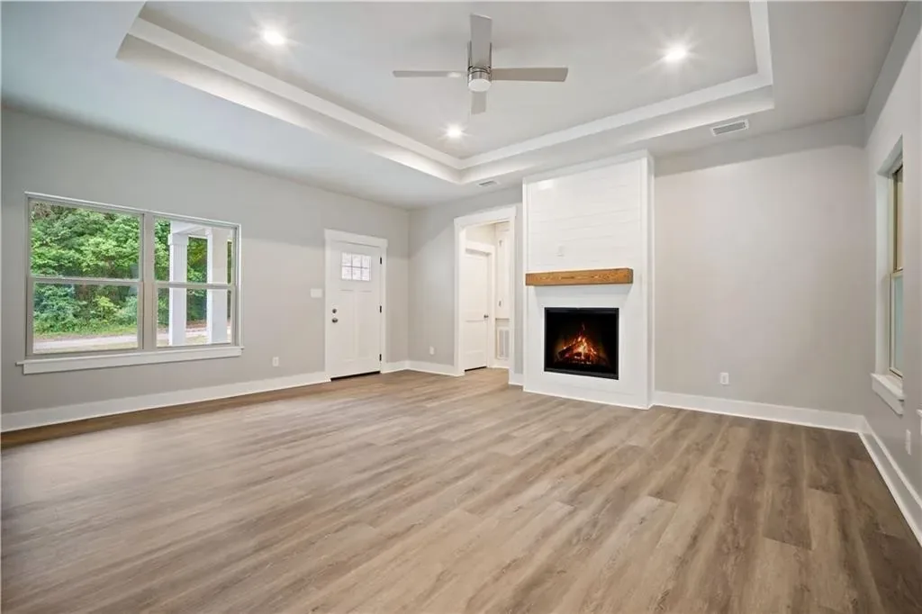 Living room with a tray ceiling, fireplace and wood flooring