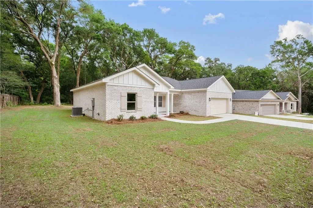 Wide view of the white brick home, garage and front lawn