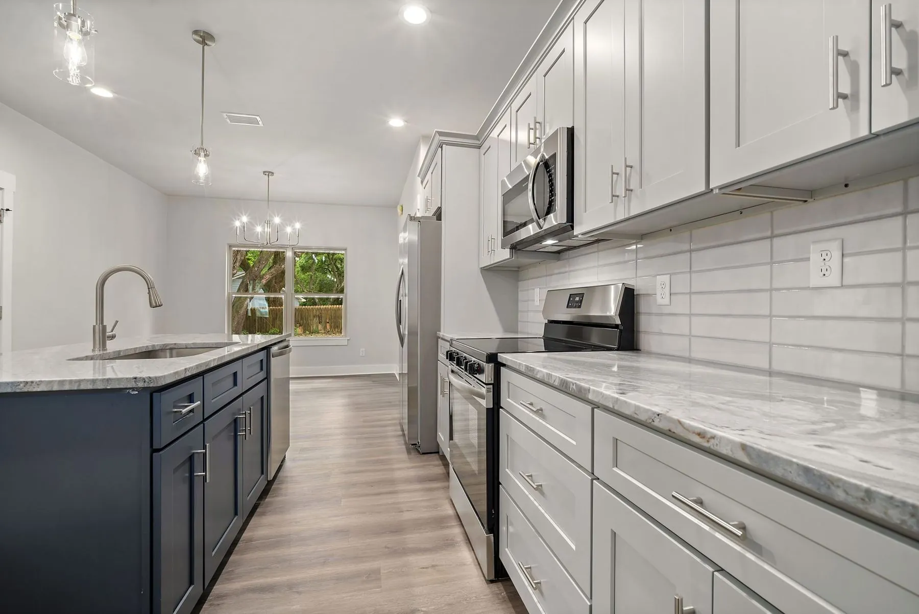 White kitchen with a dark island and stainless appliances