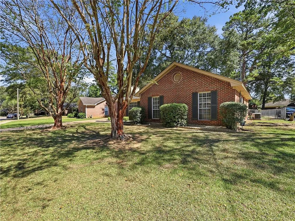 Brick home exterior with mature trees and a front lawn