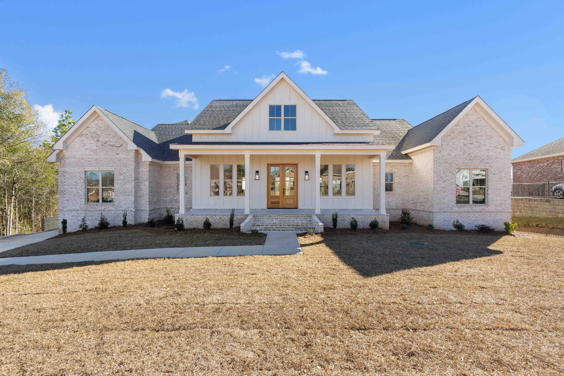 Custom farmhouse-style brick home with covered front porch built by Slone Properties
