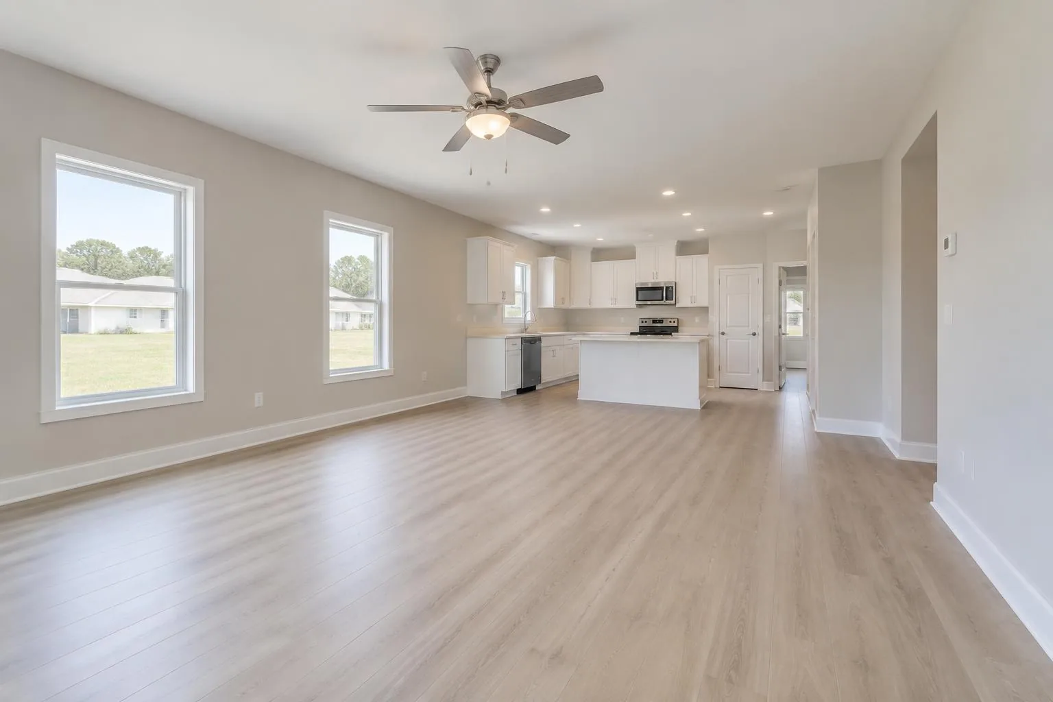 Rendering of an open duplex living room with light floors and a white kitchen